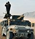 An Afghan National Army soldier stands atop a desert-camouflaged Humvee