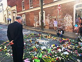 Tim Kaine inspects a makeshift memorial to Heather Heyer