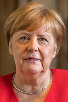 Formal portrait of Angela Merkel looking neutral in a red jacket with gold simple neckless