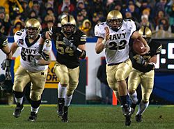 US Navy 051203-N-2383B-223 U.S. Naval Academy Midshipman fullback Adam Ballard (22) rushes for one of two touchdowns while being persued by Army defenders Cason Shrode (54) and Taylor Justice (42).jpg