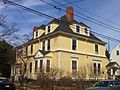 A large yellow 2 1/2 story colonial style house with white trim.