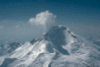 A snow-covered mountain, with a plume of steam and gas rising from the top