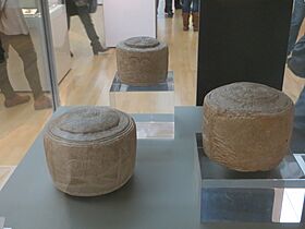 Three chalk drum-shaped objects, two sitting on perspex blocks