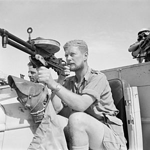 A member of a Long Range Desert Group (LRDG) patrol poses with a Vickers 'K' Gas-operated machine gun on a Chevrolet 30-cwt truck, May 1942. E12410