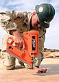US Navy 050425-N-8102P-003 Utilitesman 2nd Class John Kent, assigned to Naval Mobile Construction Battalion Two Four (NMCB-24), uses a nail gun as he helps to in build Southwest Asia huts at Camp Korean Village, in western Iraq