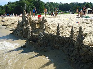 Sandcastle seen from lake with people in background