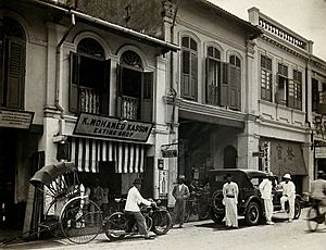 An arcade of shops with a road sweeper at work in the street of Kuala Lumpur, 1915-1925