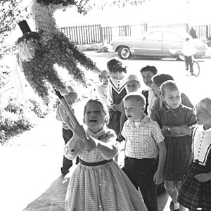 Girl striking pinata in carport of California home 1961 - 2