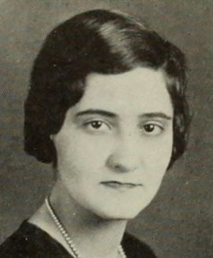 A young white woman with dark hair, in a yearbook photo. She is wearing a dark top and a strand of pearls.
