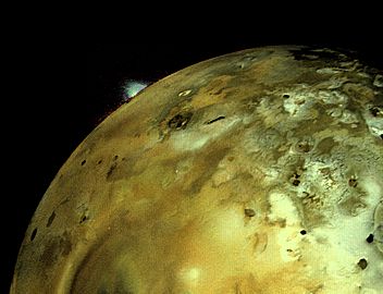 A volcanic eruption plume rises over the limb of Io