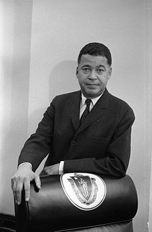 Senator Edward Brooke standing behind chair decorated with Great Seal of the Commonwealth of Massachusetts