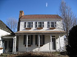 A two-story white wooden structure with a front porch on the first story