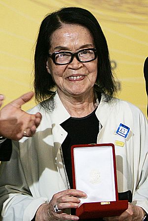 Photograph of Tomie Ohtake holding in her hands the Brazilian Order of Cultural Merit.