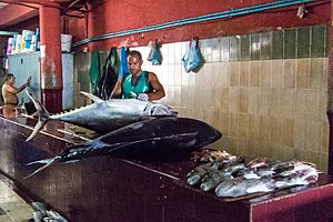 A fishmonger prepares to clean and butcher a pair of large fish in Malé