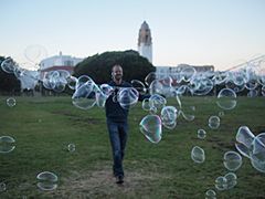 Man making bubbles in Dolores Park, with view of Mission High School