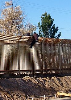 US Navy 090317-N-5253T-016 Two men scale the border fence into Mexico a few hundred yards away from where Seabees from Naval Mobile Construction Battalions (NMCB) 133 and NMCB-14 are building a 1,500 foot-long concrete-lined dr