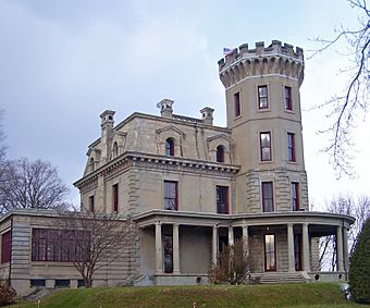 A gray house with a tower on the right side and a wing at the left.